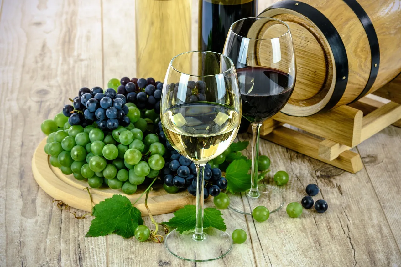 Deux verres de vin, des grappes de raisin et un tonneau sur une table en bois